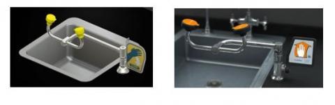 Two lab sinks with emergency eye wash stations: one with yellow nozzles, the other with orange, both featuring hand washing signs.